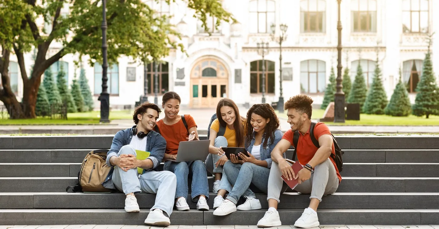 Group Of Students With Digital Tablet And Laptop Study Together Outdoors